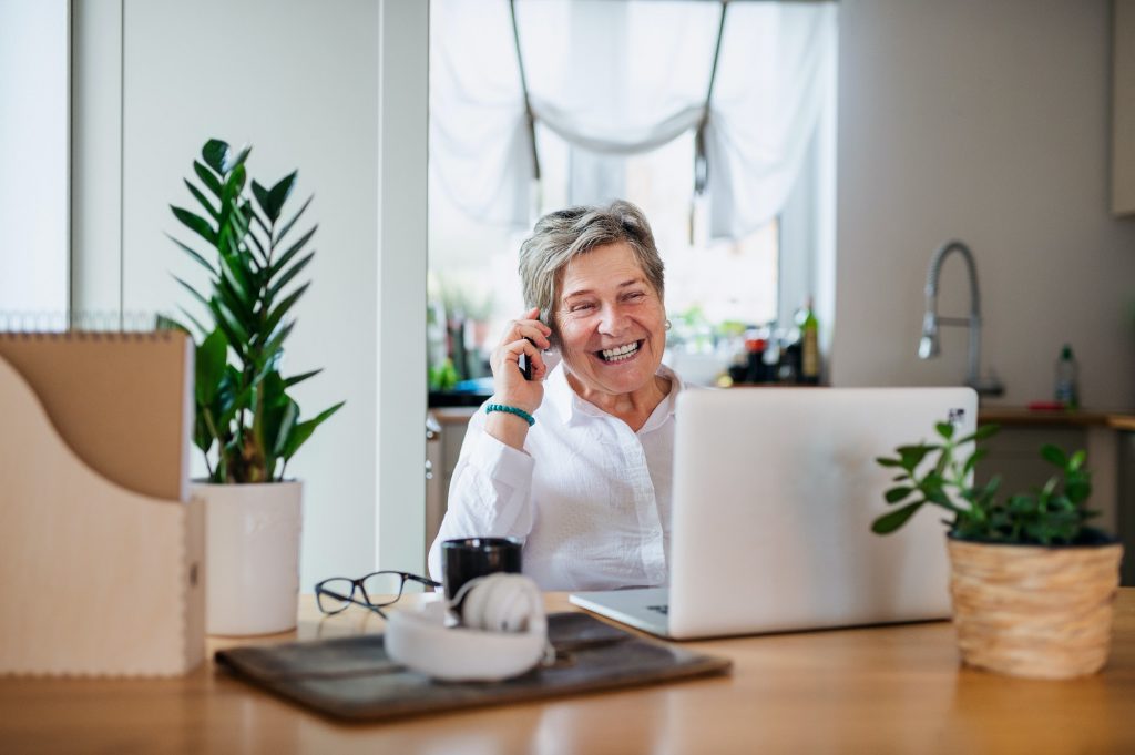 Senior woman with laptop and smartphone working in home office