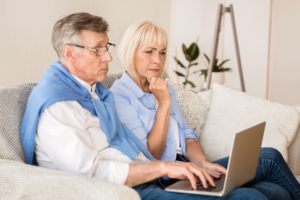 Senior couple reading news on laptop at home