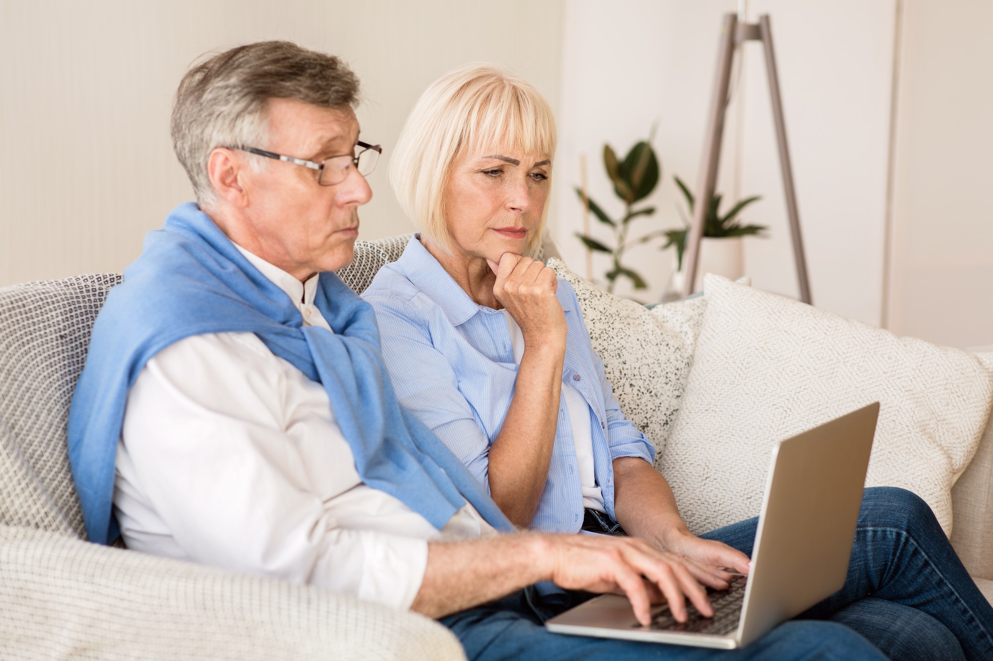 Senior couple reading news on laptop at home