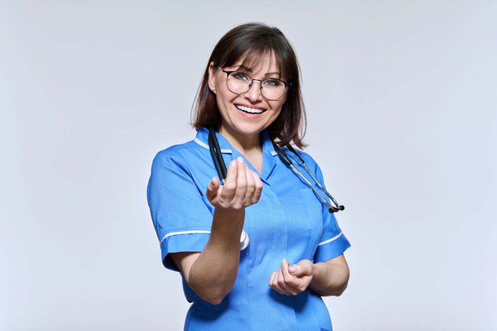 Positive smiling nurse in blue uniform looking at camera on light studio background
